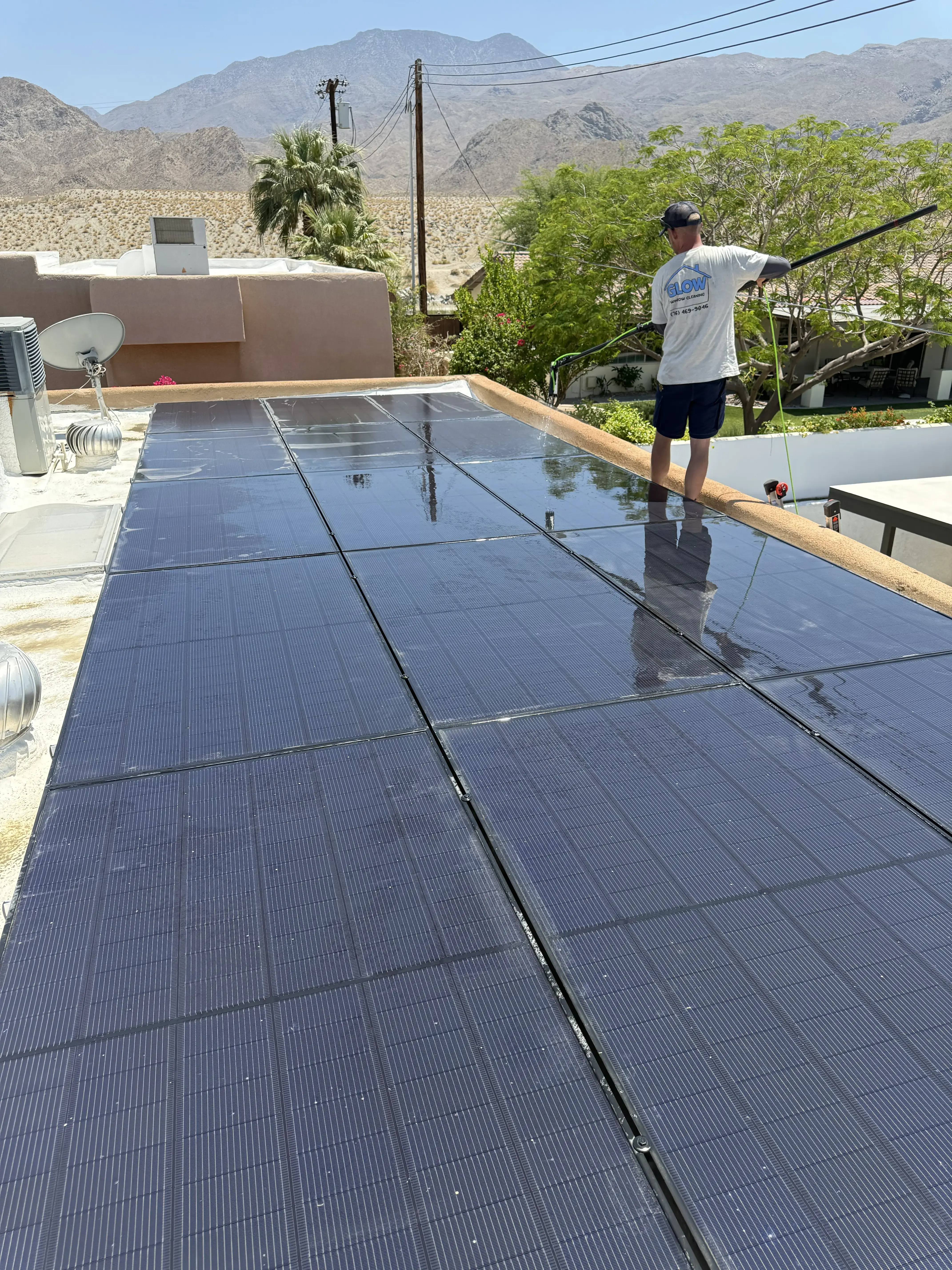 Glow technician cleaning solar panels on a residential rooftop.